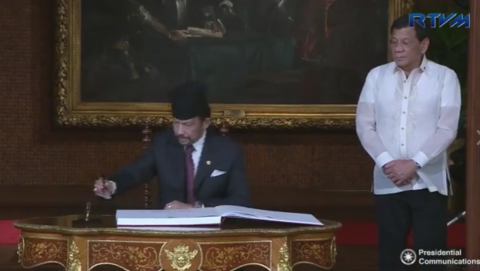 Brunei's Sultan Haji Hassanal Bolkiah signs the guest book in Malacanang Palace while Philippine President Rodrigo Duterte looks on. (Photo grabbed from RTVM video)