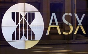 An office worker walks past the board of the Australian Securities Exchange building displaying its logo in central Sydney