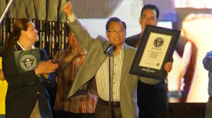 Iglesia Ni Cristo General Auditor minister Glicerio B. Santos Jr, raises his hand in jubilation after being handed the Guinness World Record award for the INC by Guinness Adjudicator Seyda Subasi Gemici.  The record for the most number of hunger relief packages distributed in eight hours (302,311 packs), single venue, is the 6th Guinness world record achieved by the INC.  (Eagle News Service) 