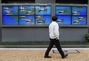 A pedestrian walks past electronic boards showing various countries' share prices outside a brokerage in Tokyo February 6, 2014. Asian shares took a tentative step forward from five-month lows on Thursday, with investors hoping the European Central Bank (ECB) and upcoming U.S. jobs data can calm nerves strained by the emerging market selloff.   REUTERS/Toru Hanai