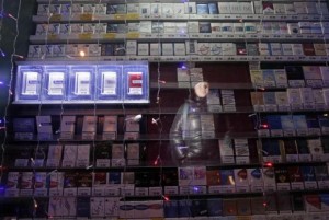  A woman is reflected in a window displaying packs of cigarettes on a street in Russia's Siberian city of Krasnoyarsk January 24, 2013. Credit: Reuters/Ilya Naymushin 