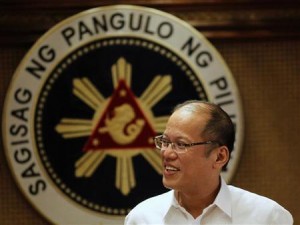 Philippine President Benigno Aquino smiles in front of a presidential seal during a government's oral immunization program for poor families at the presidential palace in Manila