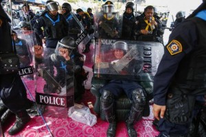 Thai riot police officers take a rest during clashes with anti-government protesters in Bangkok