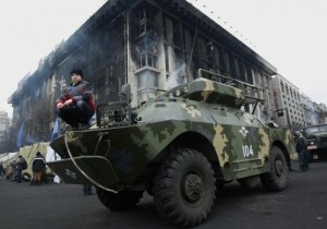 A boy poses for picture as he squats on an armored vehicle at Independence Square in Kiev February 25, 2014. REUTERS/David Mdzinarishvili