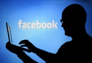 A man is silhouetted against a video screen with an Facebook logo as he poses with an Dell laptop in this photo illustration taken in the central Bosnian town of Zenica, August 14, 2013. Credit: Reuters/Dado Ruvic