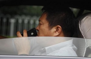 A man uses his iPhone as he drives a car along a main road in central Beijing September 24, 2012. CREDIT: REUTERS/DAVID GRAY