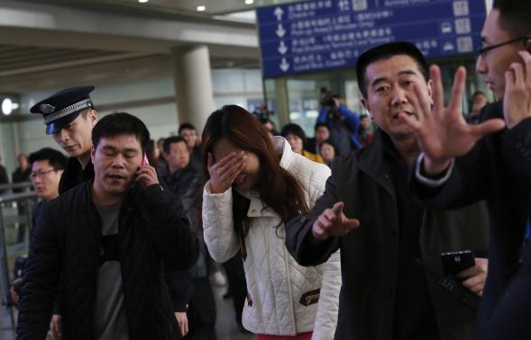 A woman (C), believed to be the relative of a passenger onboard Malaysia Airlines flight MH370, covers her face as she cries at the Beijing Capital International Airport in Beijing March 8, 2014. CREDIT: REUTERS/KIM KYUNG-HOON