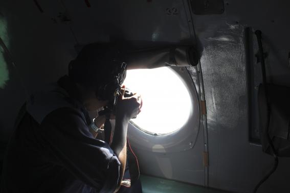A Vietnamese Air Force officer takes photos from a search and rescue aircraft in the search area for a missing Malaysia Airlines plane, 250 km from Vietnam and 190 km from Malaysia, in this handout photo from Thanh Nien Newpaper taken March 8, 2014. Mandatory Credit CREDIT: REUTERS/TRUNG HIEU/THANH NIEN NEWSPAPER