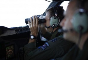 Wing Commander Rob Shearer looks through binoculars on the flight deck of a Royal New Zealand Air Force P-3K2 Orion aircraft during a search for the missing Malaysian Airlines flight MH370 over the southern Indian Ocean, March 29, 2014. Courtesy REUTERS/Jason Reed