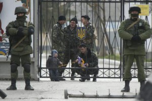 A Ukrainian serviceman plays with a child as men believed to be Russian servicemen stand in front of the gates of a Ukrainian military unit in the village of Perevalnoye outside Simferopol, March 4, 2014. REUTERS/David Mdzinarishvili