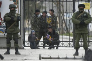 A Ukrainian serviceman plays with a child as men believed to be Russian servicemen stand in front of the gates of a Ukrainian military unit in the village of Perevalnoye outside Simferopol, March 4, 2014.  REUTERS/David Mdzinarishvili