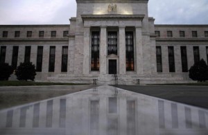 The facade of the U.S. Federal Reserve building is reflected on wet marble during the early morning hours in Washington