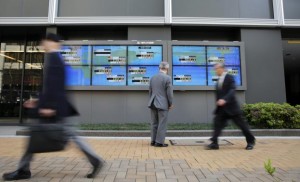 A man looks at an electronic board displaying Japan's Nikkei average (top C) and various countries' stock indices, as passers-by walk past outside a brokerage in Tokyo April 16, 2014. Credit: Reuters/Toru Hanai