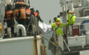 Coast guards in South Korea on Sunday (April 20) hand over more bodies found from the sunken ferry to a boat that will bring them to awaiting family members at the port. (Photo grabbed from Reuters video)