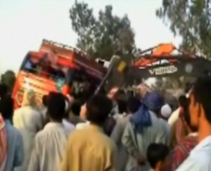 A crane tries to lift an overturned bus that clashed head-on with a vehicle pulling a trailer on the National Highway in southern Pakistan early on Sunday (April 20) (Photo grabbed from Reuters video)