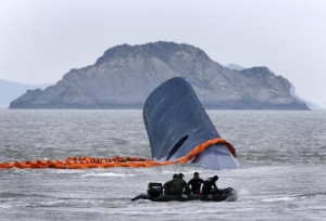 A vessel involved in salvage operations passes near the upturned South Korean ferry "Sewol" in the sea off Jindo April 17, 2014. Rescuers were hammering on the upturned hull of a capsized South Korea ferry on Thursday hoping for a response from hundreds of people, mostly teenage schoolchildren, believed trapped after the vessel started sinking more than 24 hours previously. REUTERS/Kim Kyung-Hoon  