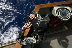Able Seaman Boatswains Mate Marc Chandler looks through a pair of binoculars aboard the Australian Navy ship HMAS Success as it continues to search for missing Malaysian Airlines flight MH370, in this picture released by the Australian Defence Force April 11, 2014. REUTERS/Australian Defence Force/Handout via Reuters