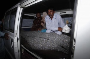 Mohammad Iqbal sits next to his wife Farzana's body, who was killed by family members, in an ambulance outside of a morgue in Lahore May 27, 2014. REUTERS/Mohsin Raza