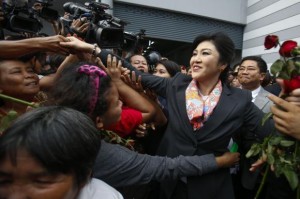 Thailand's Prime Minister Yingluck Shinawatra greets her supporters as she leaves the Permanent Secretary of Defence office in Bangkok May 7, 2014. A Thai court found Yingluck guilty of violating the constitution on Wednesday and said she had to step down, throwing the country into further political turmoil, although ministers not implicated in her case can remain in office. REUTERS/Athit Perawongmetha
