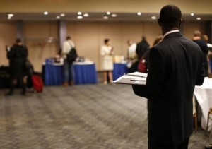 A job seeker stands in a room of prospective employers at a career fair in New York City
