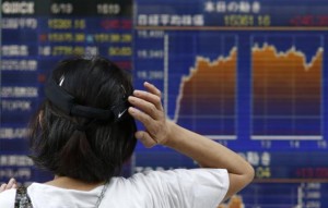 A woman scratching her head looks at an electronic board showing the graph of the recent fluctuations of Japan's Nikkei average outside a brokerage in Tokyo June 19, 2014. Credit: Reuters/Yuya Shino