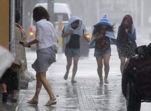 Women walk in strong winds caused by typhoon Neoguri at Kokusai street, a shopping and amusement district in Naha, on Japan's southern island of Okinawa, in this photo taken by Kyodo July 8, 2014. REUTERS/Kyodo
