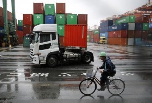 A worker rides a bicycle in a container area at a port in Tokyo May 21, 2014. Credit: Reuters/Toru Hanai