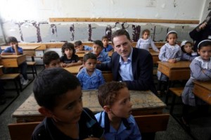 Pierre Krahenbuhl, United Nations Relief and Works Agency (UNRWA) Commissioner-General, sits with Palestinian students inside a classroom as he visits a United Nations-run school on the first day of a new school year in Khan Younis in the southern Gaza Strip September 14, 2014. REUTERS/Ibraheem Abu Mustafa