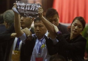 Pro-democracy lawmaker Wu Chi-wai (C) from the Democratic Party is grabbed by security guards as he protests against Li Fei, deputy general secretary of the National People's Congress (NPC) standing committee, who is speaking at a briefing session in Hong Kong September 1, 2014. REUTERS/Bobby Yip