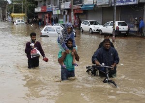 A Kashmiri man evacuates an elderly woman to a higher ground at a flooded road in Srinagar September 7, 2014. REUTERS/Danish Ismail