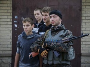 Boys pose for pictures with a Ukrainian serviceman as he stands guard in Volnovakha, Donetsk region, September 11, 2014. Courtesy REUTERS/Gleb Garanich
