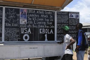 Bystanders read headlines saying "Ebola 1: USA 0" at the Daily Talk, a street side chalkboard newspaper, in Monrovia October 16, 2014. REUTERS/James Giahyue