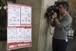 A video journalist films a sign asking patients to inform staff if they have fever, cough, trouble breathing, rash, vomiting or diarrhea symptoms and have recently traveled internationally or have had contact with someone who recently traveled internationally at Bellevue Hospital in Manhattan, New York October 8, 2014. REUTERS/Adrees Latif