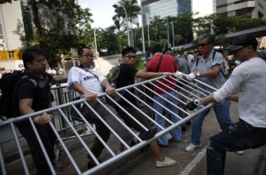 Pro-democracy protesters (L) scuffle with  anti-Occupy Central protesters (R) as they grab a metal fence at the main protest site in Admiralty in Hong Kong October 13, 2014. REUTERS/Carlos Barria