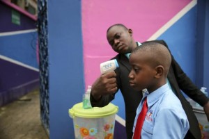 A school official takes a pupil's temperature using an infrared digital laser thermometer in front of the school premises, at the resumption of private schools, in Lagos in this September 22, 2014 file photo. REUTERS/Akintunde Akinleye/Files