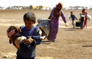 A young Syrian Kurdish refugee boy carries an infant after crossing the Syrian-Turkish border, near the southeastern town of Suruc in Sanliurfa province on Sept. 23, 2014. (Reuters/Murad Sezer)