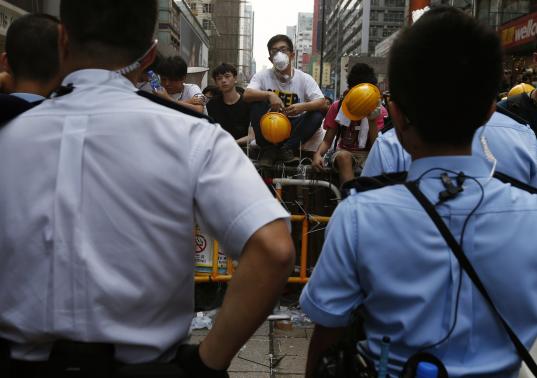 Pro-democracy protesters man a barricade from being demolished by anti-Occupy protesters, in front of a police patrol line at Mongkok shopping district in Hong Kong October 22, 2014. CREDIT: REUTERS/BOBBY YIP