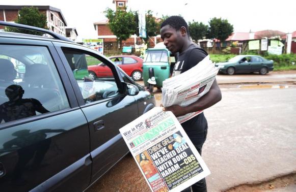 A newspaper vendor stands along road as he holds newspapers with a front page headline reading 'Chibok girls: We've reached deal with Boko Haram', in Abuja October 18, 2014. REUTERS/Stringer