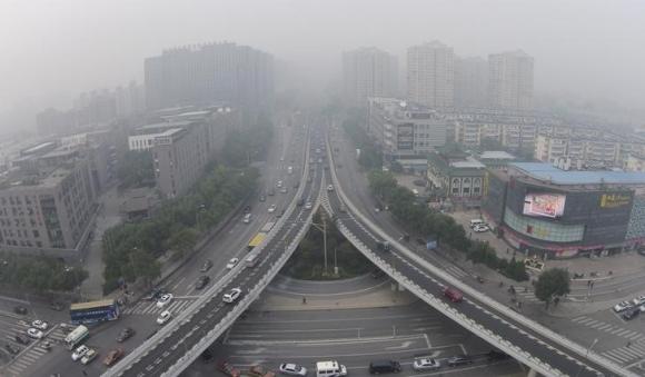 Vehicles and buildings are seen amid the heavy haze in Beijing, October 9, 2014. CREDIT: REUTERS/JASON LEE/FILES