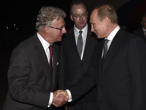 Russia's President Vladimir Putin (R) shakes hands with Governor of Queensland Paul de Jersey (L) as Official Secretary to Australia’s Governor-General Mark Fraser looks on, after arriving at the G20 Terminal in Brisbane in this November 14, 2014 picture provided by G20 Australia. CREDIT: REUTERS/G20 AUSTRALIA/HANDOUT VIA REUTERS