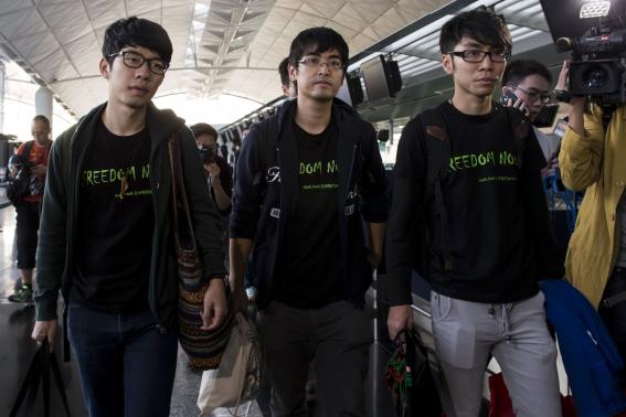 Hong Kong Federation of Students leader Alex Chow (C), committee members Nathan Law (L) and Eason Chung react after being refused to board the plane at the Hong Kong International Airport November 15, 2014. CREDIT: REUTERS/TYRONE SIU