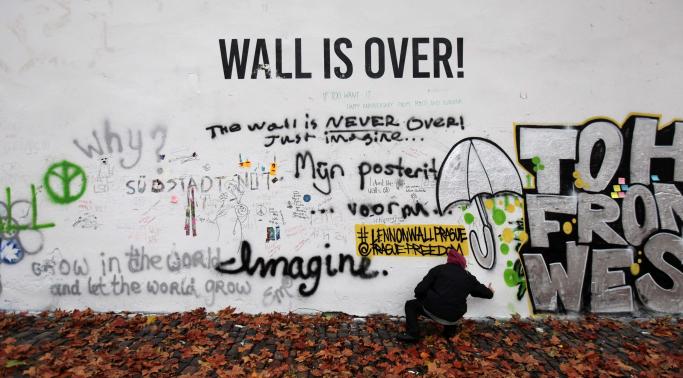 A man sprays graffiti on the legendary John Lennon Wall in the historical centre of Prague November 18, 2014. CREDIT: REUTERS/DAVID W CERNY