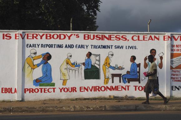 A man walks by a mural with health instructions on treating the Ebola virus, in Monrovia, November 18, 2014. CREDIT: REUTERS/JAMES GIAHYUE