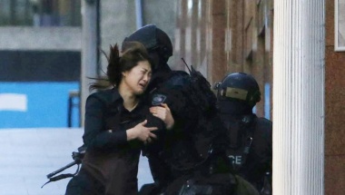 A hostage runs towards a police officer outside Lindt cafe, where other hostages are being held, in Martin Place in central Sydney December 15, 2014. Two more hostages have run out of the cafe at the center of a siege in Sydney, Australia's largest city, according to a Reuters witness at the site. The two women were both wearing aprons indicating they were staff at the Lindt cafe where a gunman has been holding an unknown number of hostages for several hours. Three men had earlier run out of the cafe.   REUTERS/Jason Reed (AUSTRALIA - Tags: CRIME LAW TPX IMAGES OF THE DAY)