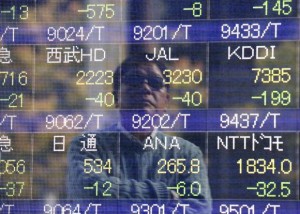 A man is reflected on an electronic stock quotation board outside a brokerage in Tokyo