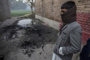 A boy stands where people said Taliban gunmen burnt a car to block a road outside the Army Public School, which was attacked by Taliban gunmen, in Peshawar December 17, 2014. REUTERS/Zohra Bensemra