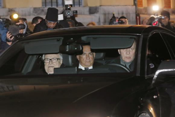Journalists surround the car as former IMF head Dominique Strauss-Kahn (C, backseat of car) leaves after the first day of trial in the so-called Carlton Affair, in Lille, February 2, 2015, where 14 people including Strauss-Kahn stand accused of sex offences including the alleged procuring of prostitutes. CREDIT: REUTERS/GONZALO FUENTES