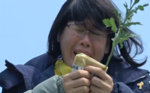 A female relative of one of the Sewol ferry disaster victims cries as she holds a white chrysanthemum.  Some 200 relatives of the more than 300 South Korean students who drowned in the ferry disaster visited the site of the sinking a year after the tragedy.  (Photo grabbed from Reuters video/Courtesy Reuters)