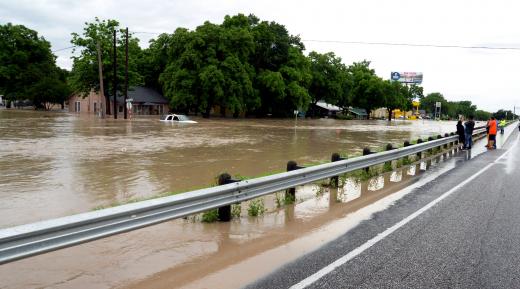 People stand on an interstate highway as flood water covers the roads businesses and houses in San Marcos, Texas May 24, 2015. REUTERS/Don Anders/Anders Photography/Handout