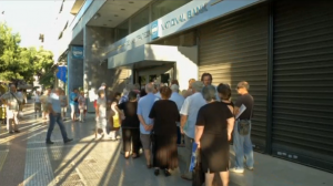 Greek pensioners queue outside banks to receive their pension payments, while others line up at cash machines as reserves start to run low. (Photo grabbed from Reuters video)